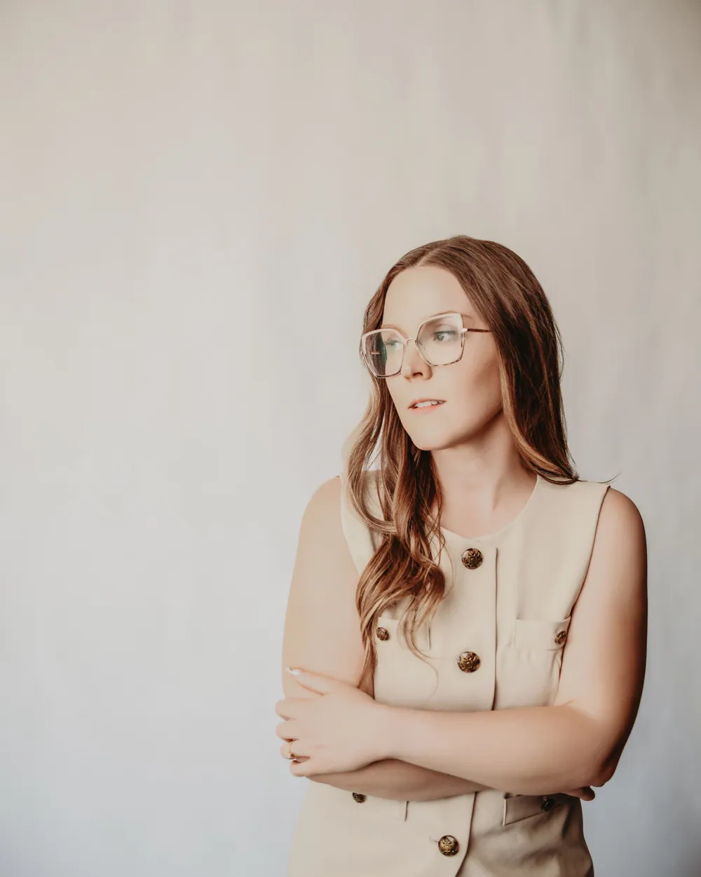 Andrea Wade in a cream vest, arms crossed, looking off to the side