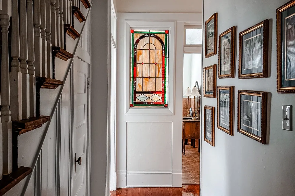 Interior hallway with a stained glass window, staircase, and wood floors