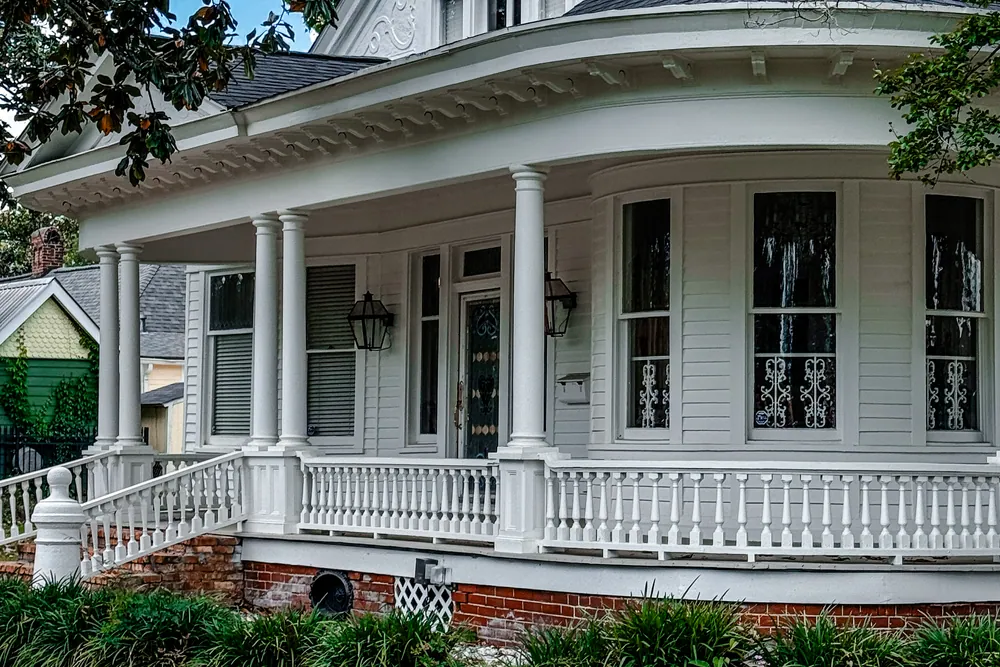 The curved colonnade of a white Louisiana home with iron railings