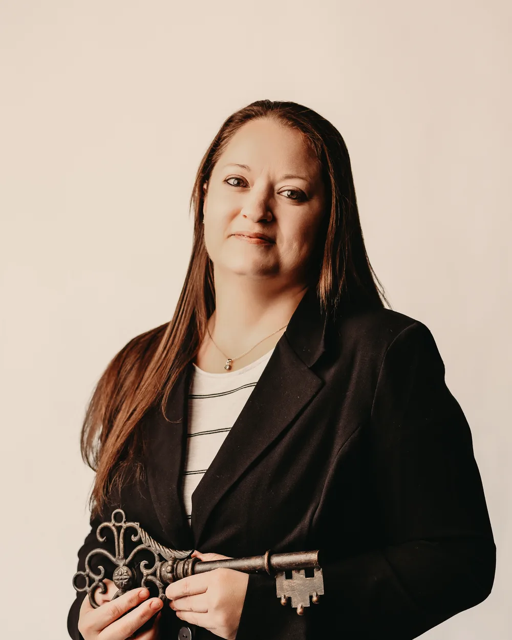 Darlene Firmin, Realtor, in a dark blazer holding an ornamental key